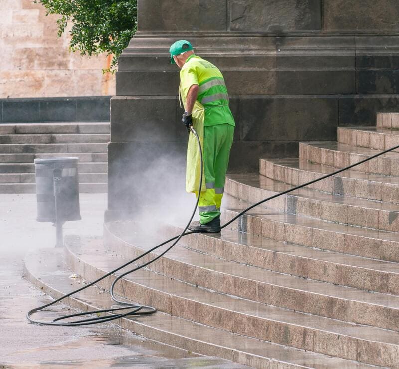 Tech pressure washing residential driveway